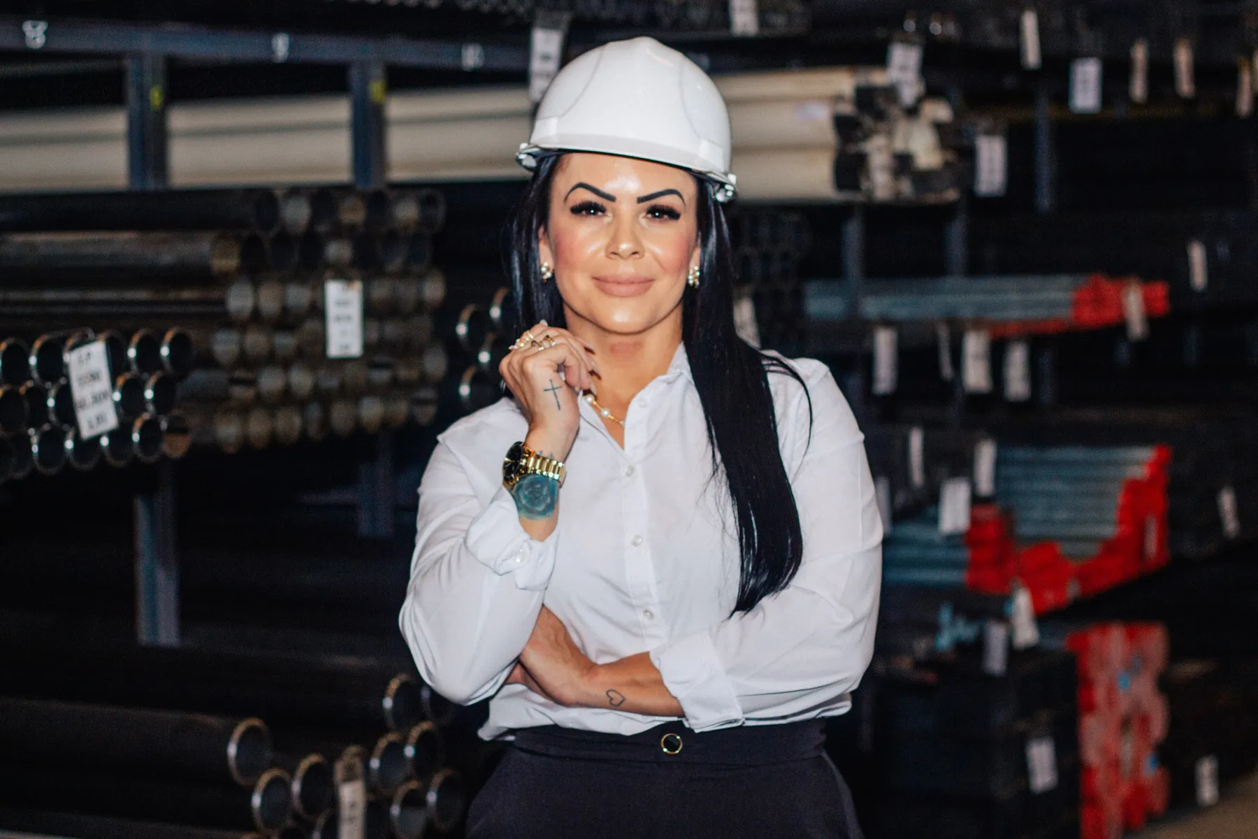 Alessandra Santos sorrindo no estoque de tubos de aço da Cronos Metal